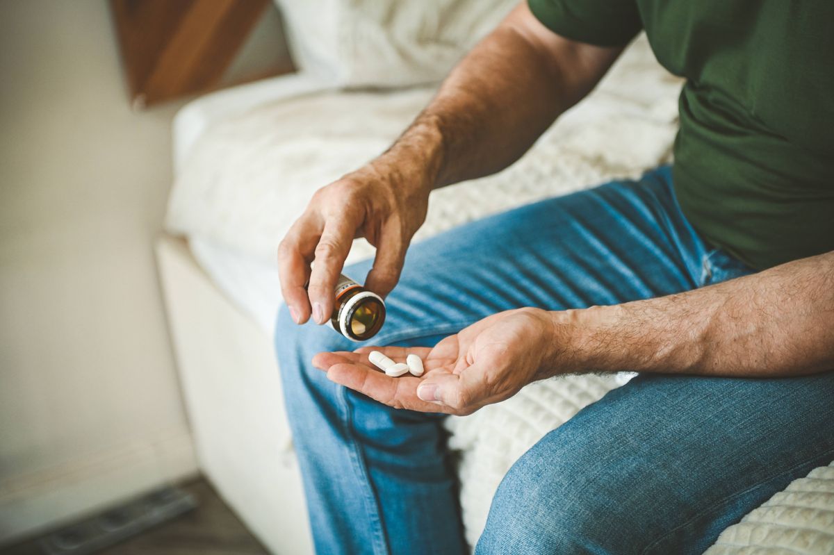 Mature adult man in the interior of a bedroom taking medication