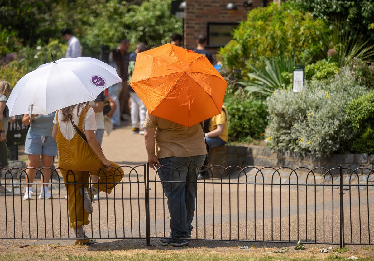 People shelter from the sun beneath umbrellas at St James's Park in central London.