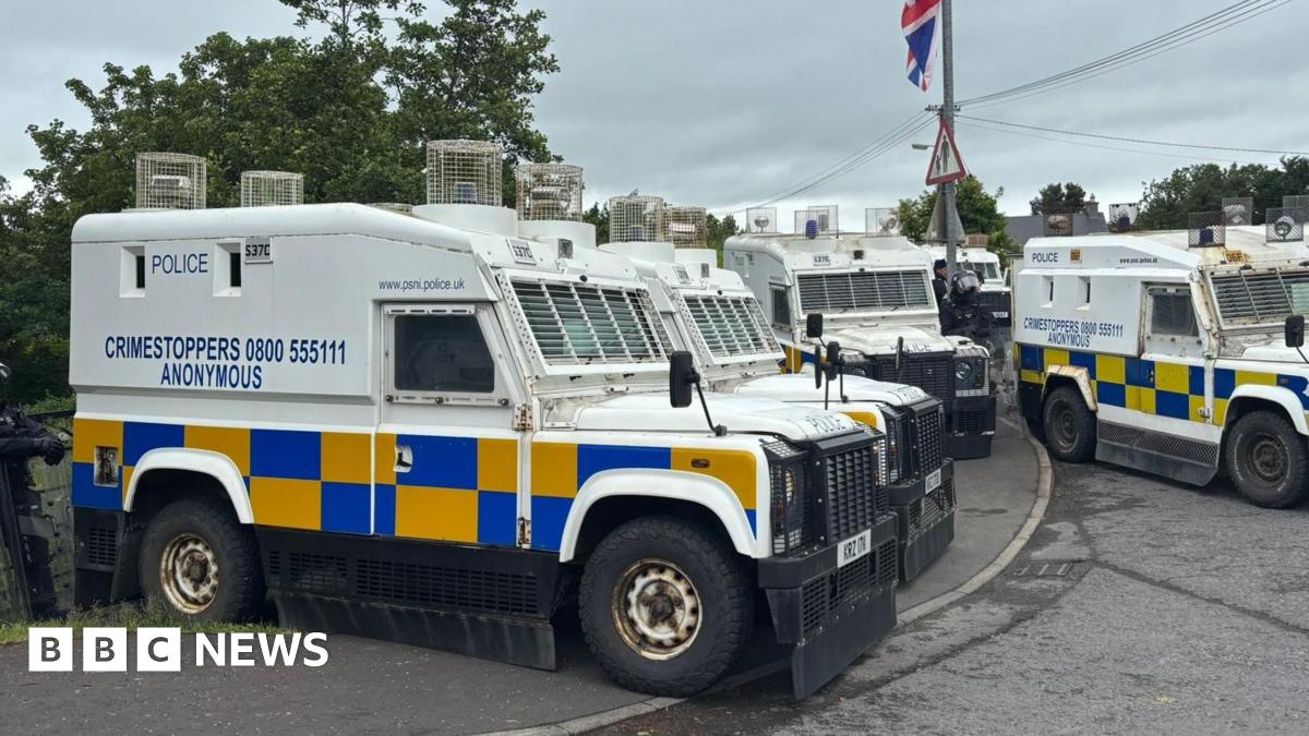 A number of Police Service of Northern Ireland landrovers are seen parked up beside a bridge in the village of Scarva ahead of the arrival of a Palestine solidarity parade. A Union Jack flag can also be partially seen at the top of the picture attached to a lamp post.