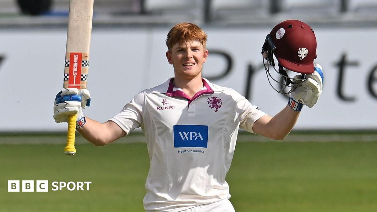 Thomas Rew raises his bat and helmet to celebrate scoring his maiden century