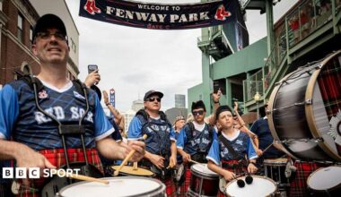 A pipe band outside Fenway Park wearing tartan tops bearing the words "Rex Sox"