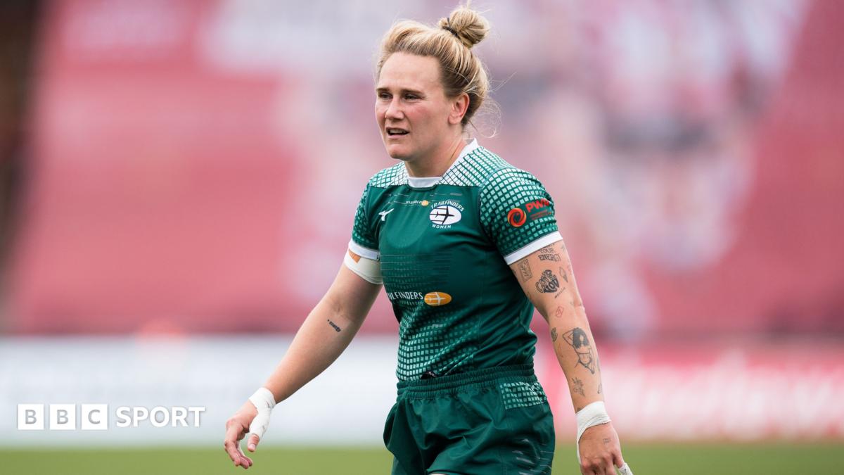 Meg Jones looks on, wearing the green home kit of Ealing Traifinders, showing a number of tattoos down her left arm.