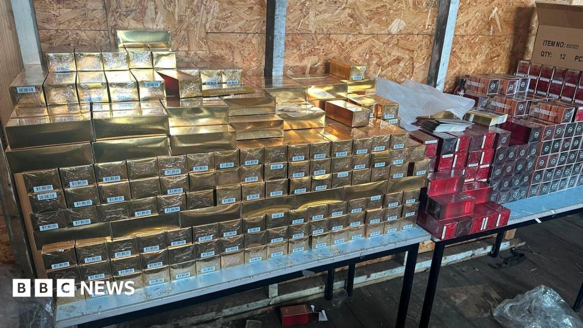 Stacks of gold packages and red packages which look to be perfume packaging stacked on a table.