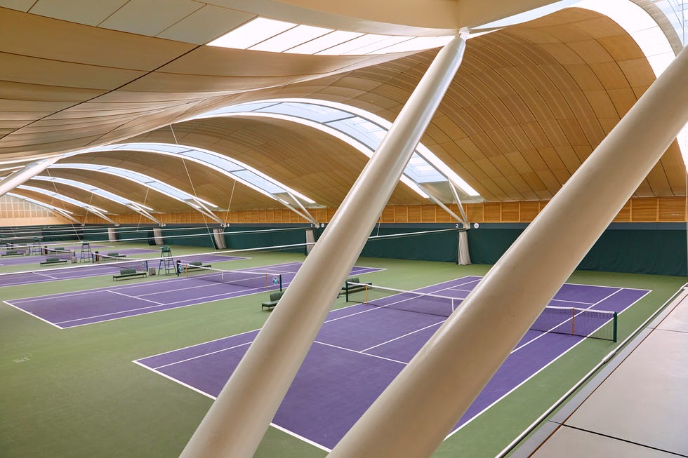 Indoor tennis courts with purple surfaces and curved wooden ceiling.