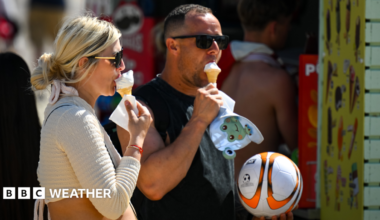 A man and a woman eating ice cream cones in the sunshine