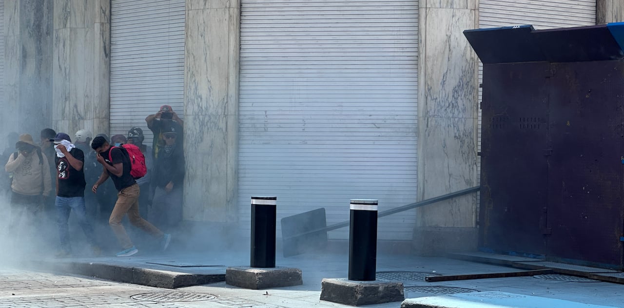 A group of masked people run from smoke.