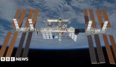 The International Space Station is seen in the centre of the image in space orbiting the Earth