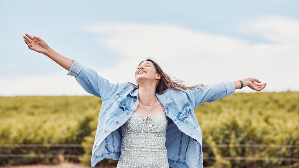 Happy, freedom and smile with woman in nature for peace, relax and youth with blue sky mockup. Journey, adventure and happiness with girl enjoying outdoors for summer break, vacation and holiday