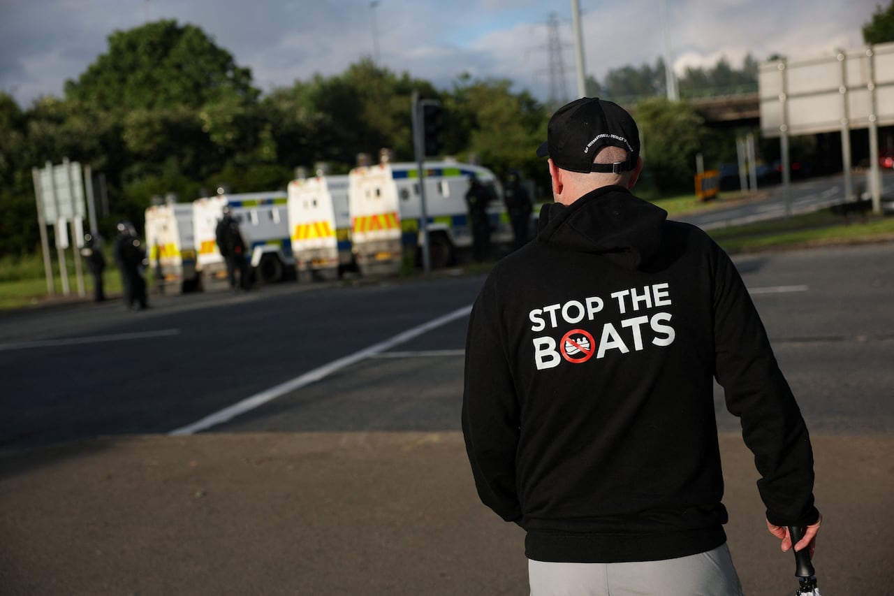 A man wears a 'Stop the Boats' hoody, as police and their vehicles block a road to stop anti-immigrant protesters from reaching Sandyknowes Roundabout, following a knife attack on June 8, which left a man seriously injured and prompted police to decl