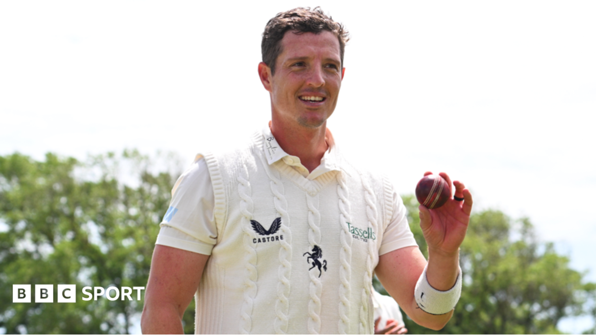 Keith Dudgeon, wearing Kent whites, holds up the ball at the end of the Lancashire innings to celebrate taking six wickets