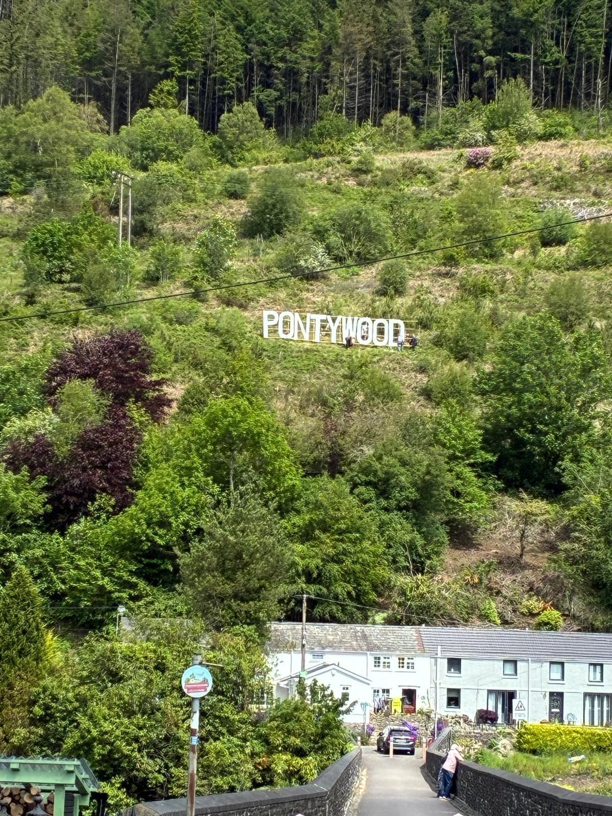 A sign on a hill of a Welsh village