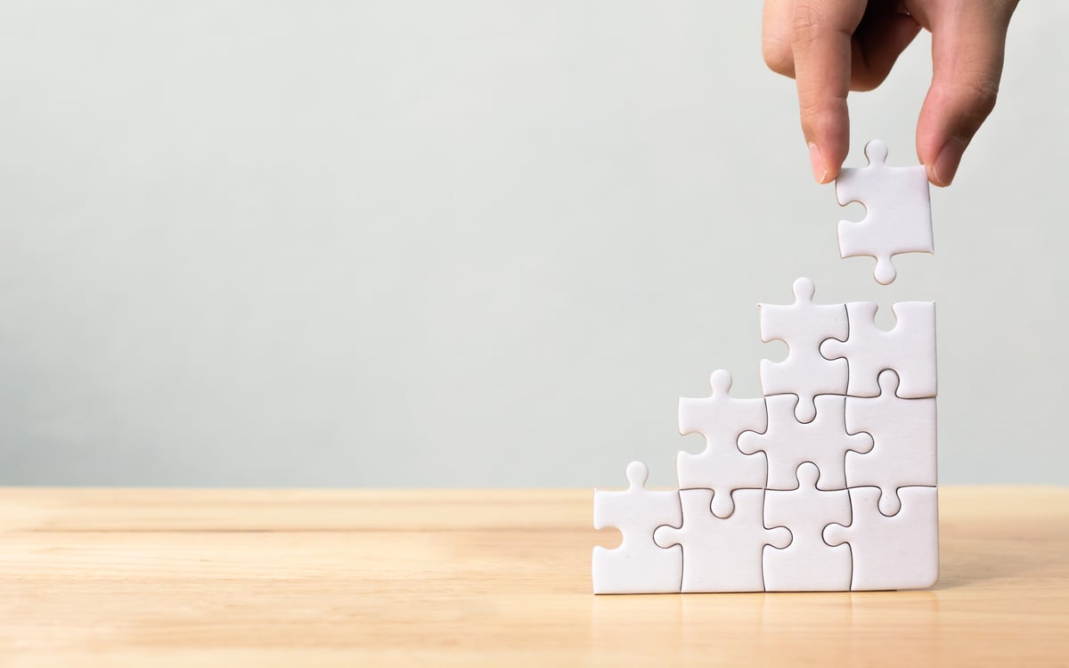 A hand building a puzzle vertically.