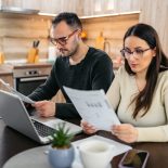 Mid-Adult Couple Calculating Their Finances On The Laptop In The Kitchen - stock photo