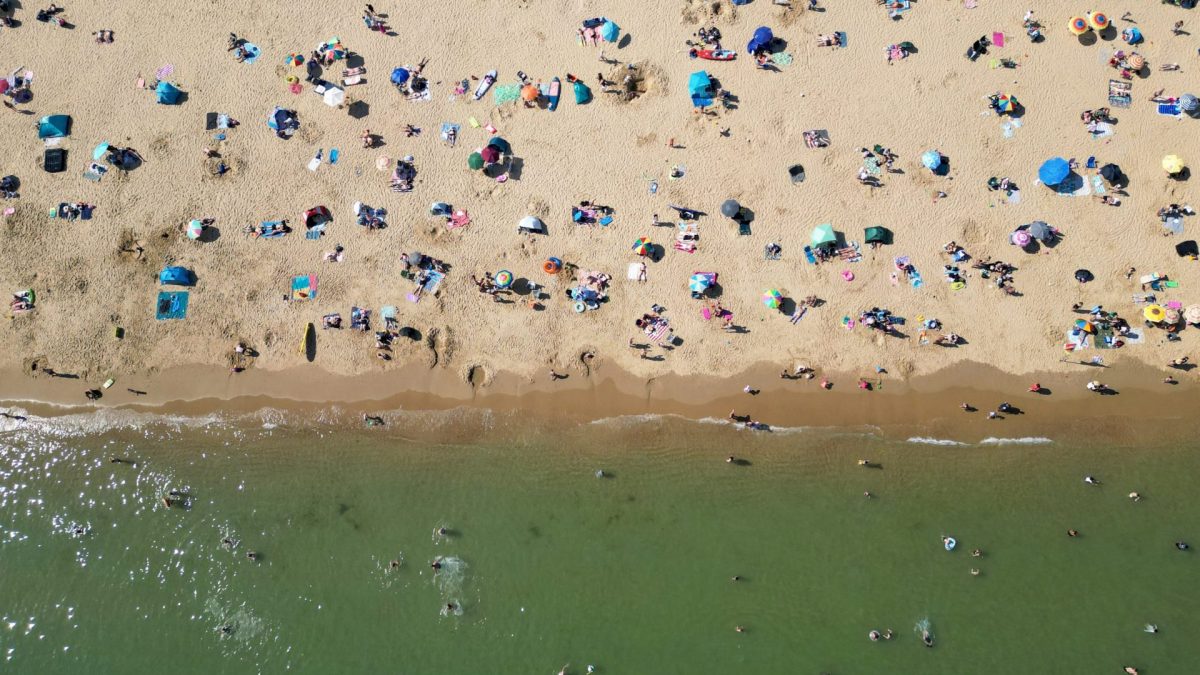 TOPSHOT - An aerial picture shows people playing in the sea and relaxing in the sunshine on Bournemouth beach on the south coast of England on May 26, 2026, as heatwave conditions spread to parts of southeast England and London. Britain registered on Tuesday its hottest-ever May temperature on record, with the mercury rising to 35C near the capital. (Photo by JUSTIN TALLIS / AFP via Getty Images)