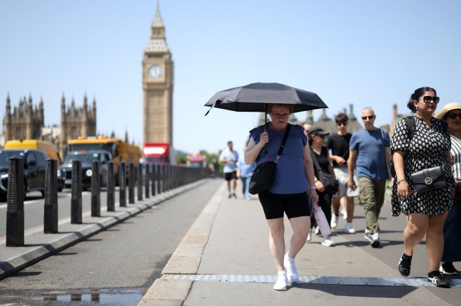A person uses an umbrella to shelter from the direct sun, on a hot summer's day,in London on June 23, 2026.