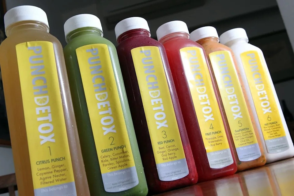 Six bottles of Punch Detox juice are lined up, each labeled with a number and flavor, including Citrus, Green, Red, and others