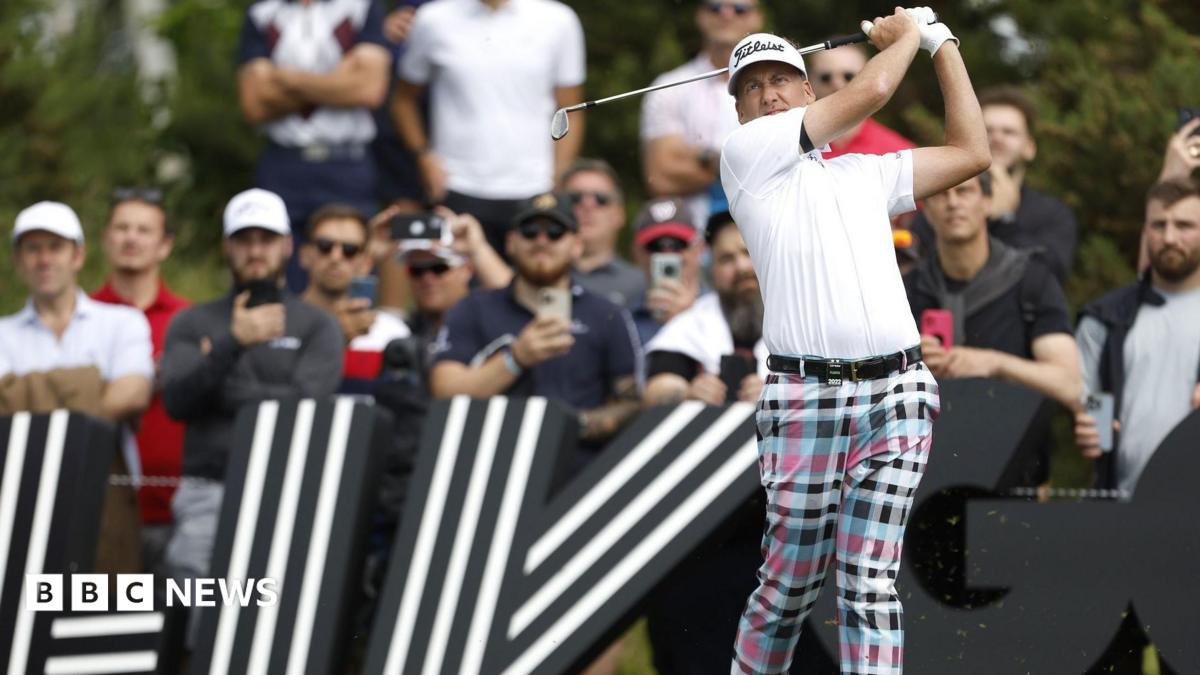 Ian Poulter in the middle of a follow-through after hitting a shot during a professional tournament. In the background are large black signs featuring bold white striped graphics.