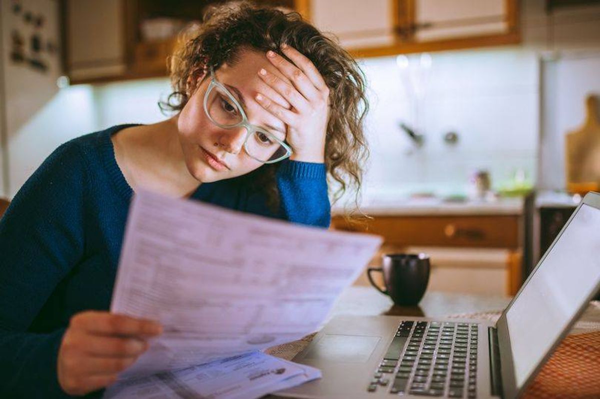 A woman is looking at a form with a worried expression. 