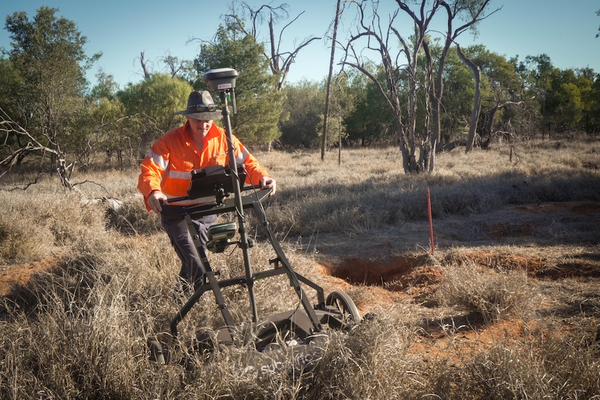 A man pushes a lawnmower-type device