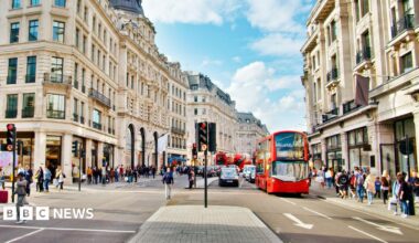 Regent Street in London is pictured with a red bus stopped at light and people walking on the footpath