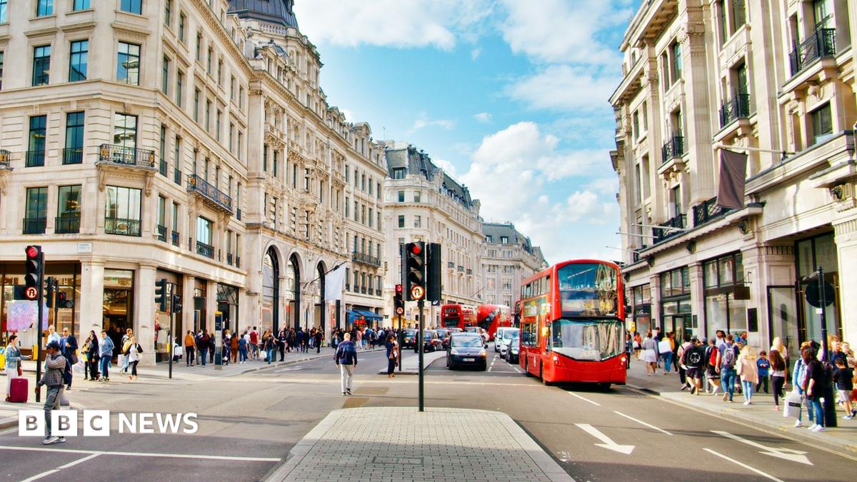 Regent Street in London is pictured with a red bus stopped at light and people walking on the footpath