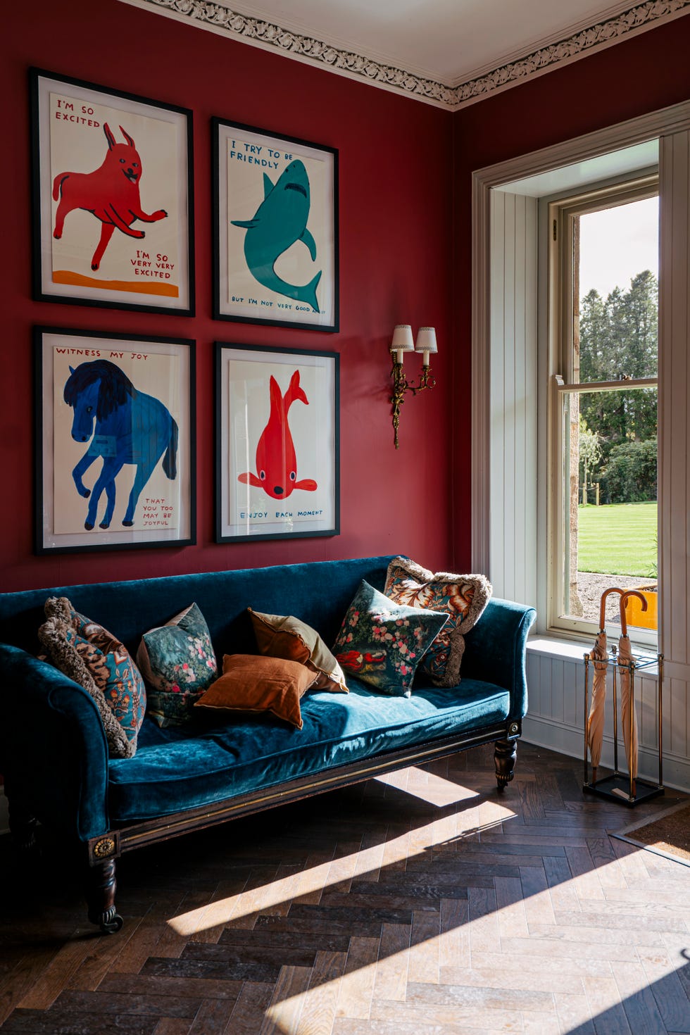 cozy corner with framed animal art a velvet couch and a window view
