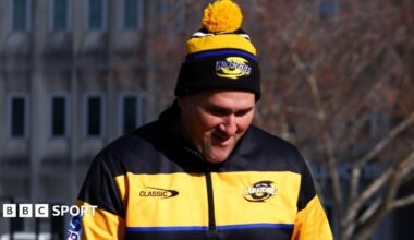 Brad Cooper in a yellow and black jacket and bobble hat, smiling with his head bowed slightly