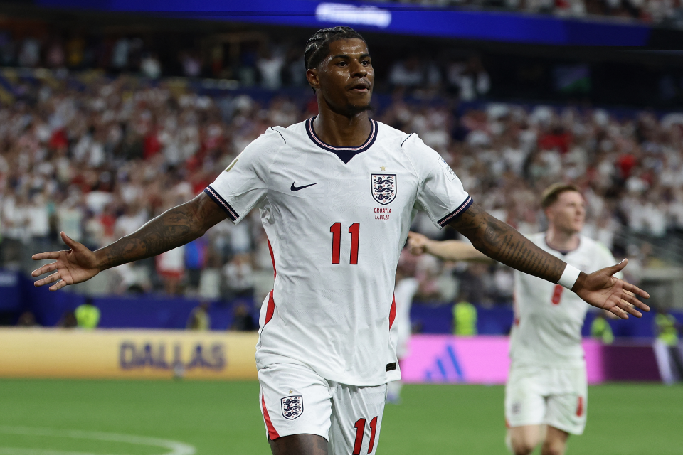 Marcus Rashford of England, wearing a white kit, celebrates with his arms outstretched after scoring for England against Croatia at the 2026 World Cup.