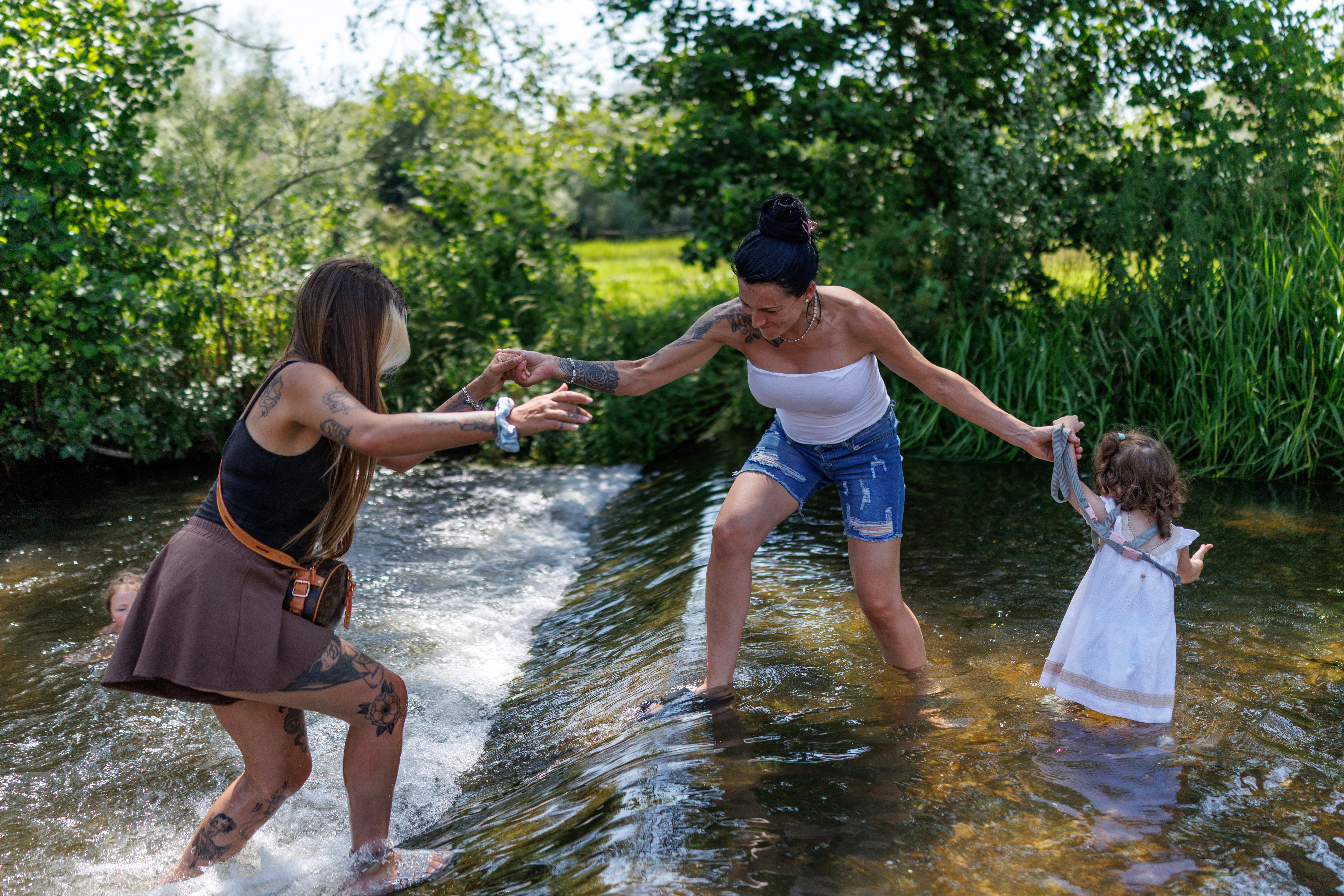 Sasha (centre) with her daughter Maureen (right) and friend Sammi (left) cool off in the River Darent on 19 June 2026 in Eynsford, United Kingdom
