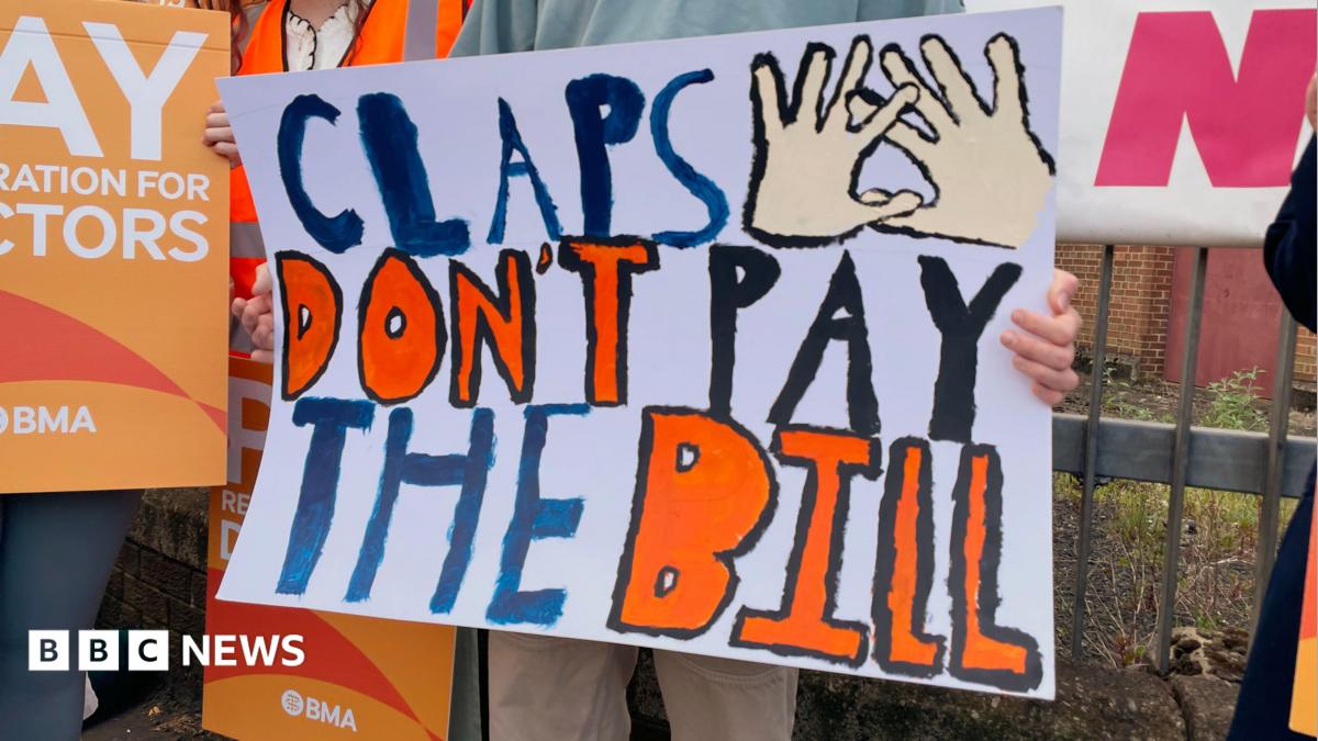 A group of people striking, one has a banner that says claps don't pat the bill.
