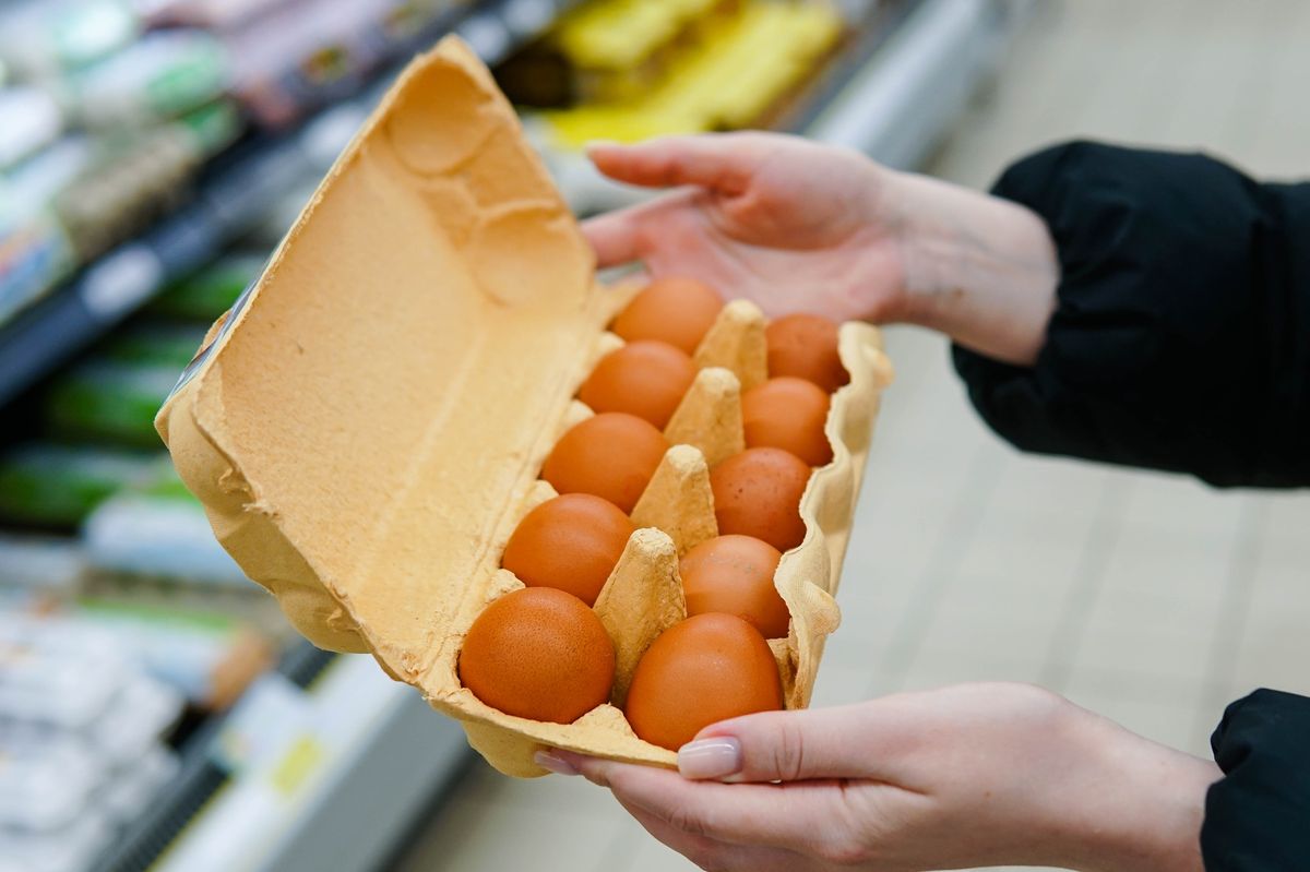 Woman chooses chicken eggs in a grocery store. Close up.