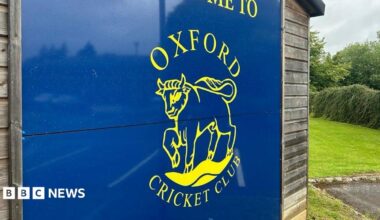 A blue sign with the Oxford Cricket Club logo, which is an ox, in yellow.