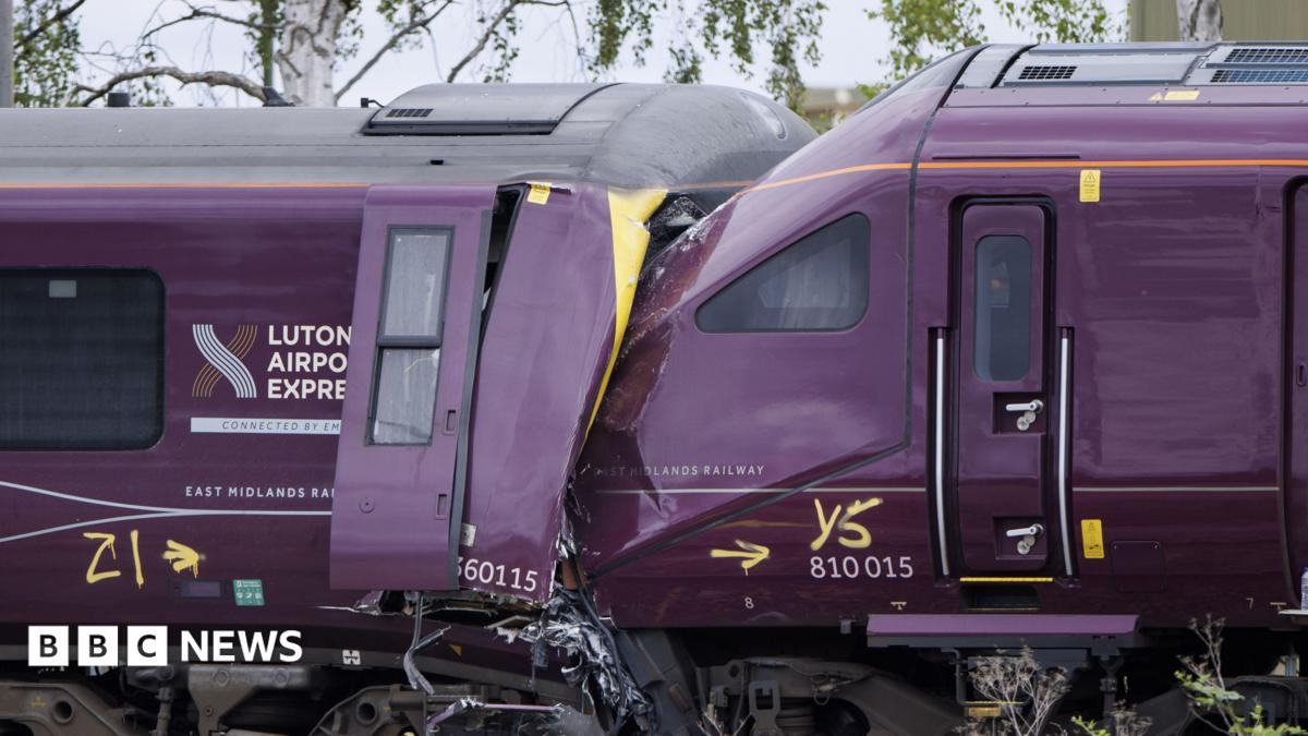 Two trains that have collided. One train is badly damaged. The driver's cab is crumpled and twisted.