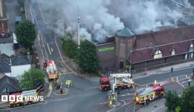 Several fire engines surround a smouldering supermarket.