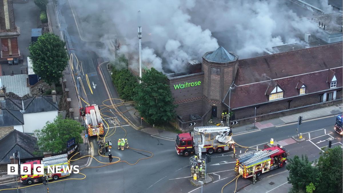 Several fire engines surround a smouldering supermarket.