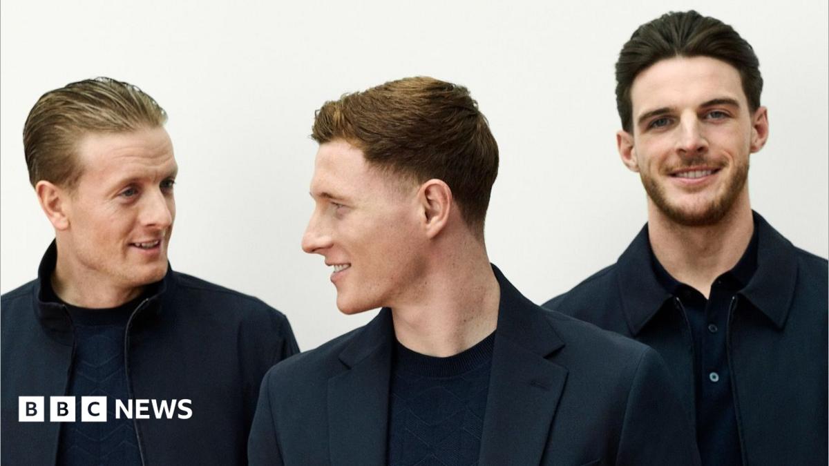 England men's squad wearing dark jackets and trousers, standing with their arms folded in front of them