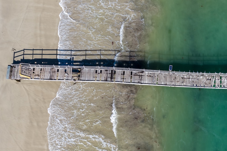 A drone shot of a jetty with planks missing. 
