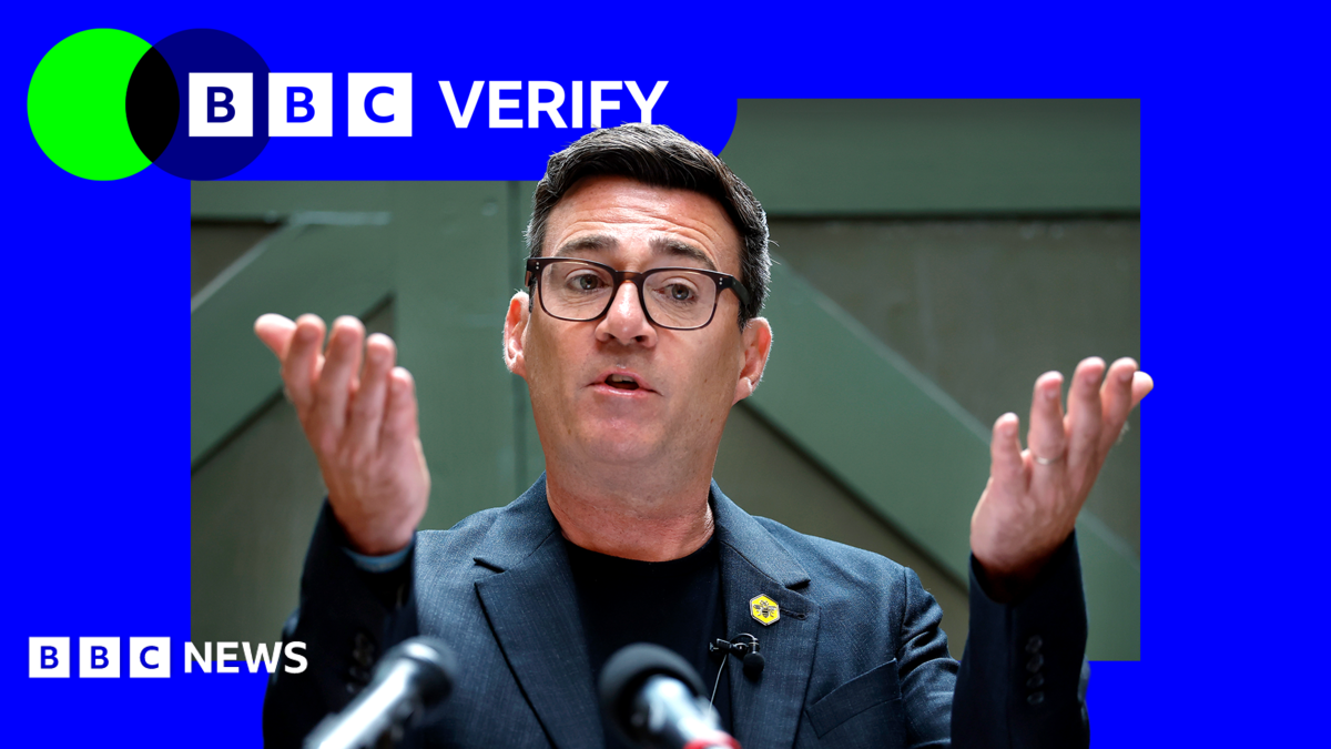 Andy Burnham holds his hands up in front of him as he delivers a speech