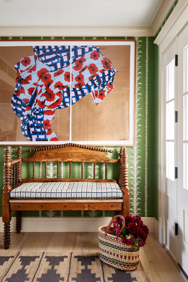 Wooden bench below floral artwork and basket with flowers.