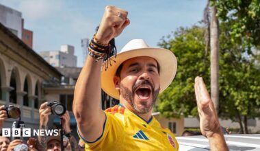 Abelardo de la Espriella cheers, wearing a hat and football shirt.