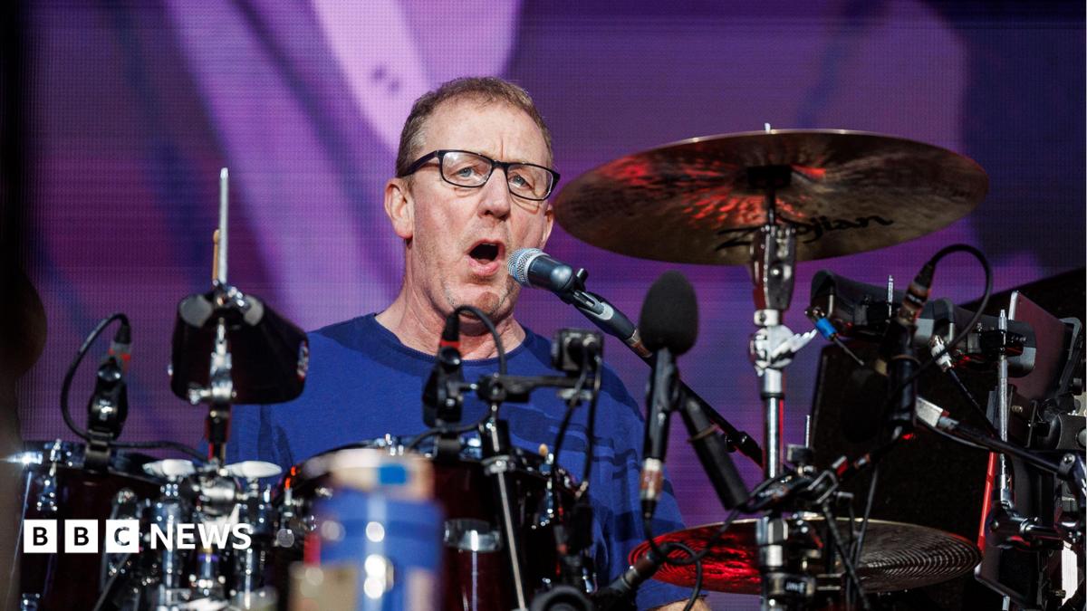 A man, Dave Rowntree, playing drums on a stage.