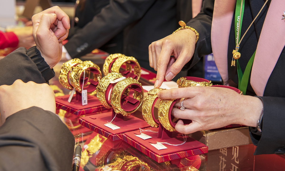 A sales representative shows a piece of gold jewelry at an expo in Guangzhou, South China