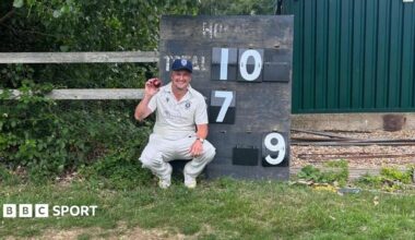 David York holding a ball in front of the scoreboard