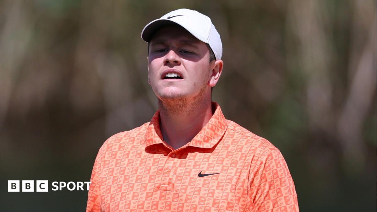 Close up of Bob MacIntyre with his cap casting a shadow over his face as he watches a putt go towards the hole
