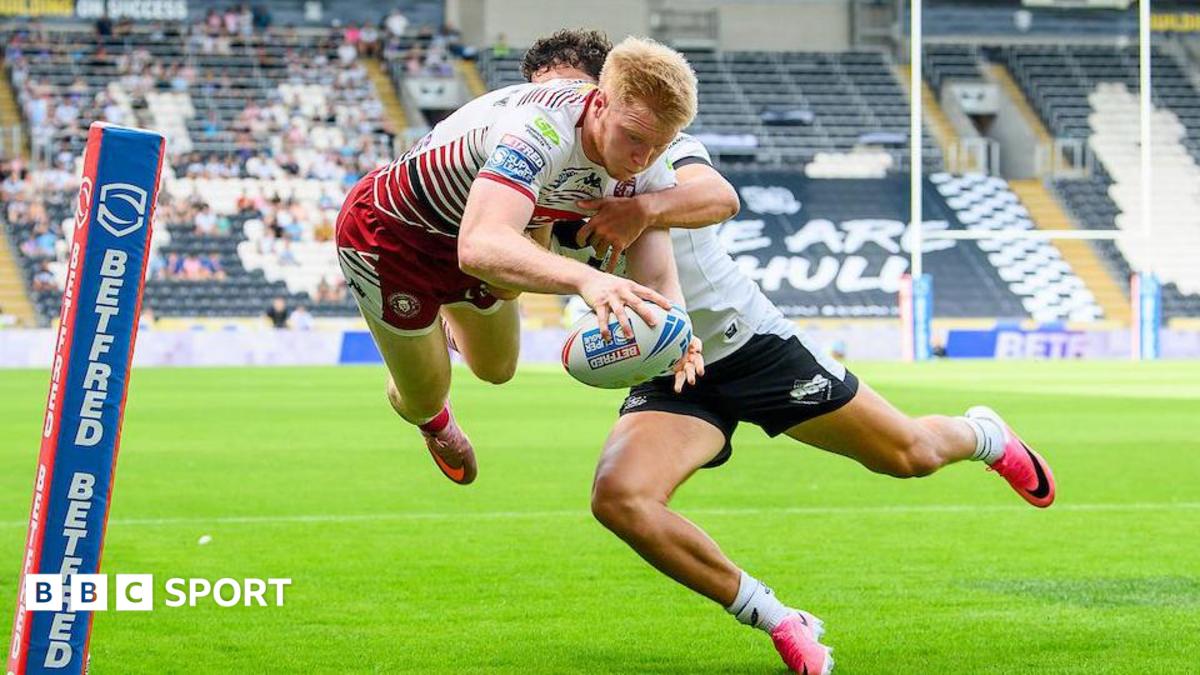 Wigan's Zach Eckersley leaps in the air while challenged by a Hull player to score a one-handed try