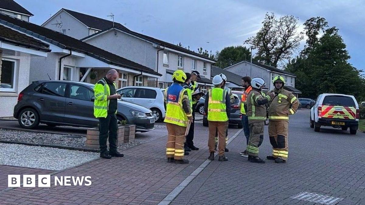 Emergency services gather in a residential street with a taped off cordon in the foreground