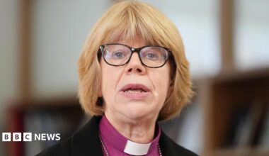 Dame Sarah Mullally, who has a blonde bob hairstyle with a fringe and wears glasses with a dark frame, is pictured speaking at a previous event at Chapter House in Canterbury Cathedral