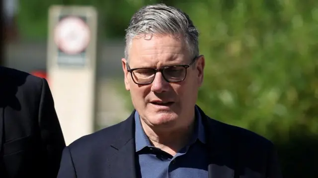 Britain's Prime Minister Keir Starmer wearing a suit and glasses with head bowed.