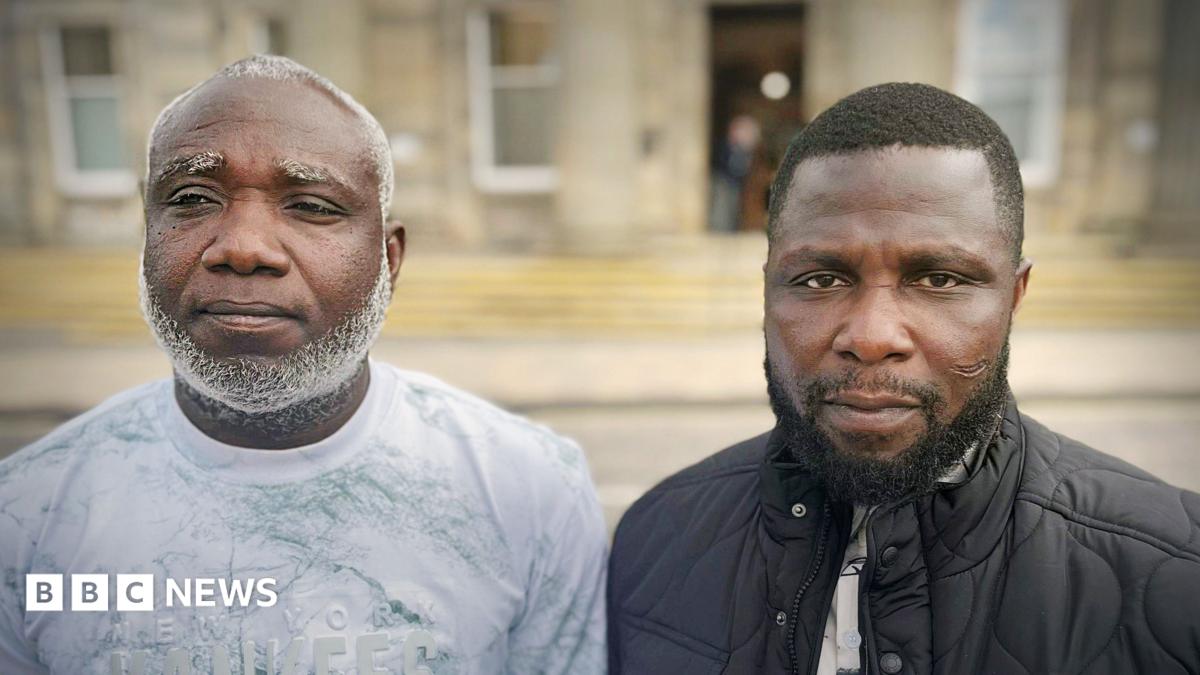 Two men shown side-by-side in a split portrait, both facing the camera outdoors in front of a blurred building. The man on the left has a short haircut with a grey beard and is wearing a light-coloured patterned shirt, while the man on the right has short hair, a trimmed beard, and is wearing a dark quilted jacket over a shirt.