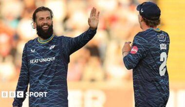 Yorkshire player Moeen Ali smiles and holds up his hand in celebration as he is approached by team-mate Dom Bess.